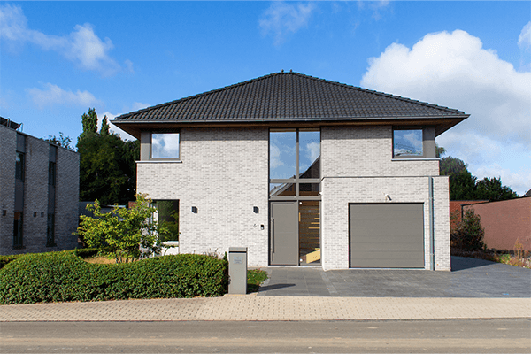 Voorgevel van een moderne alleenstaande woning in Koolskamp met strakke architectuur en lichtrijke ramen.