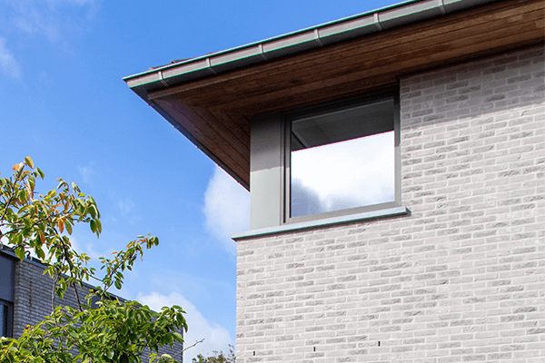 Detail van de gevel met lichtgrijze gevelsteen en raamprofielen in moderne nieuwbouw Koolskamp.