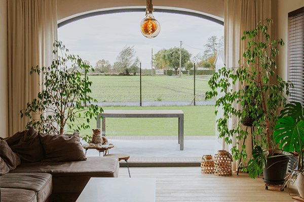 Lichte woonkamer van een nieuwbouwvilla in Lichtervelde met grote raampartijen en zicht op de tuin.